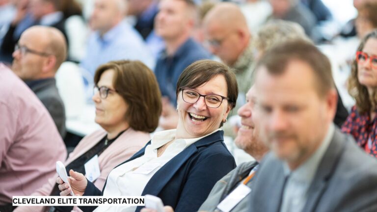Business professionals smiling and networking during a conference session, representing productivity supported by stress-free, luxury transportation.