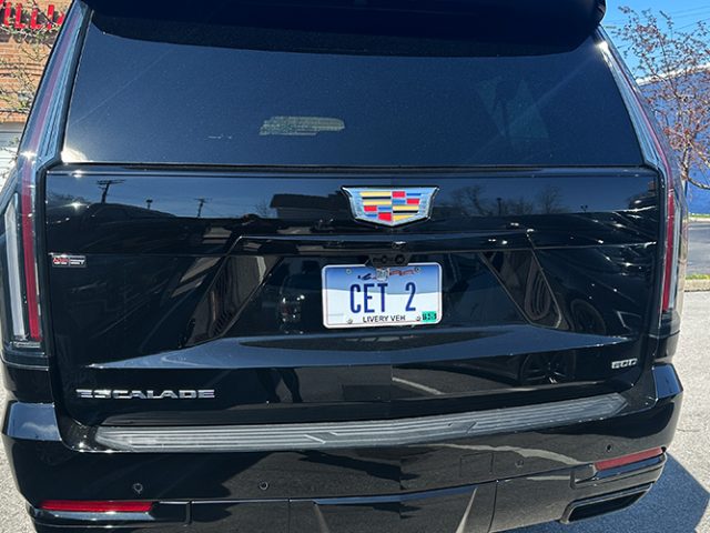 Rear view of a black Cadillac Escalade SUV parked outdoors, showing the tailgate, Cadillac emblem, and a license plate reading CET 2.