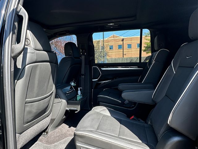 Leather SUV interior showing two middle-row captain's chairs and a center console with a hand sanitizer bottle on the armrest.